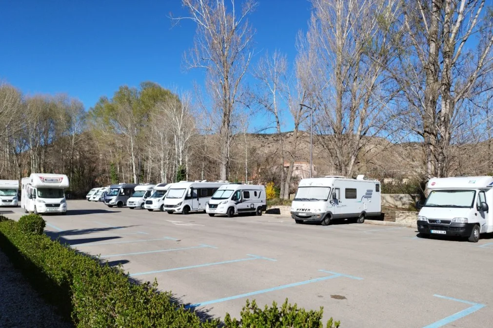 Área de autocaravanas de Albarracín, con campers y autocaravanas aparcadas entre los chopos
