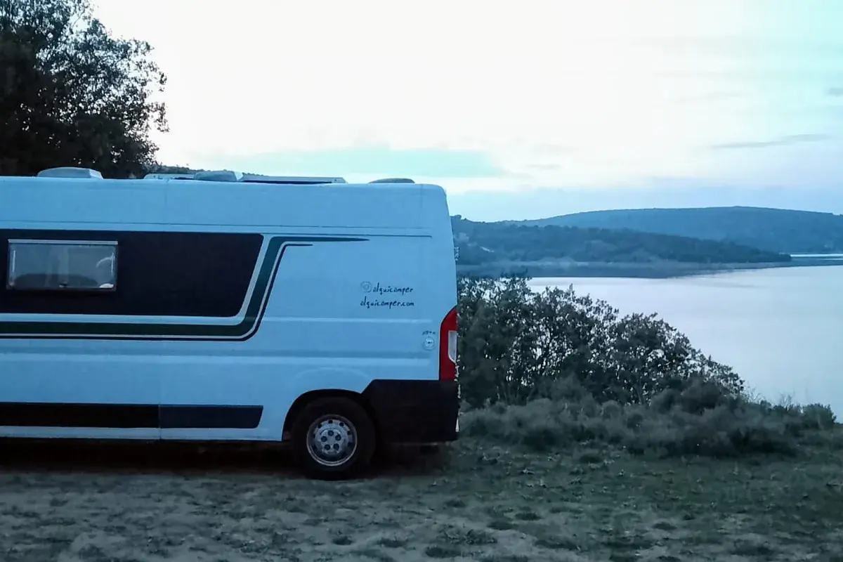 Camper aparcada junto a un lago en plena naturaleza durante una pernocta libre
