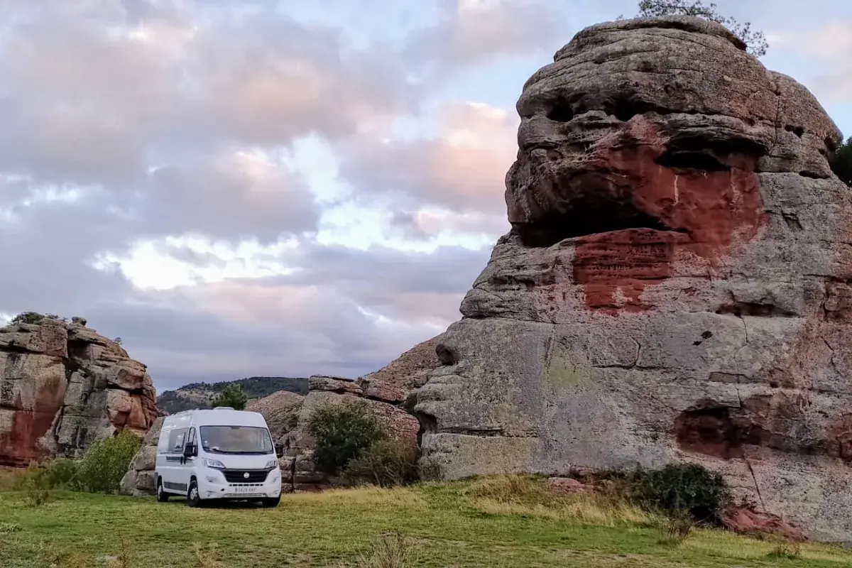 Furgoneta camper en ruta por España, aparcada junto a formaciones rocosas rojizas