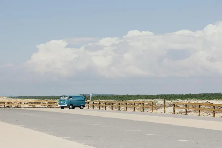 Furgoneta camper Volkswagen T2 aparcada en camino de arena junto a la costa para pernocta