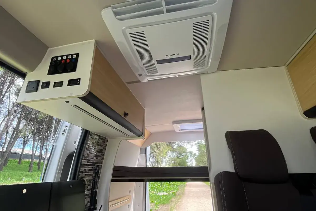 Interior de una camper con cocina de gas, panel de mandos, zona de asientos y claraboya